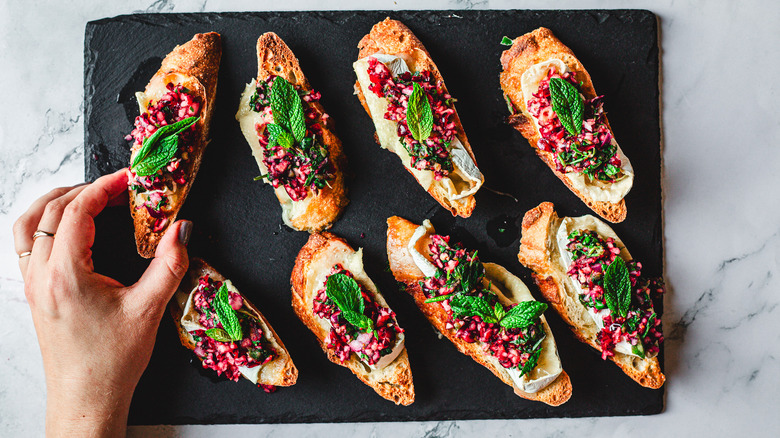 Grabbing one of the crostini on black cutting board