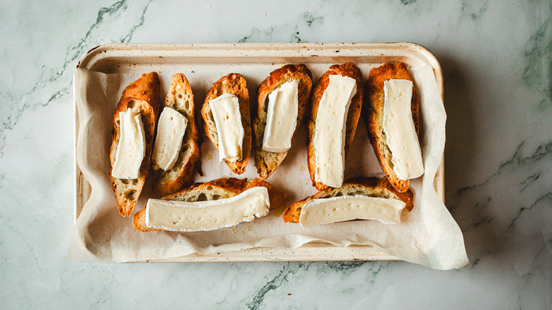 Brie and baguette slices on baking sheet