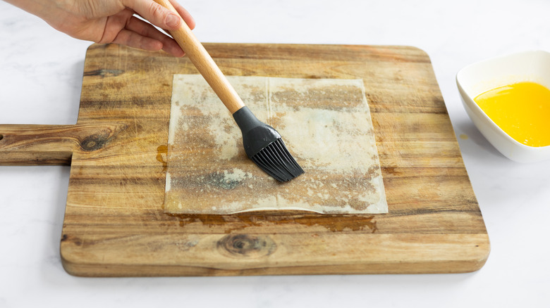 brushing melted butter onto pastry