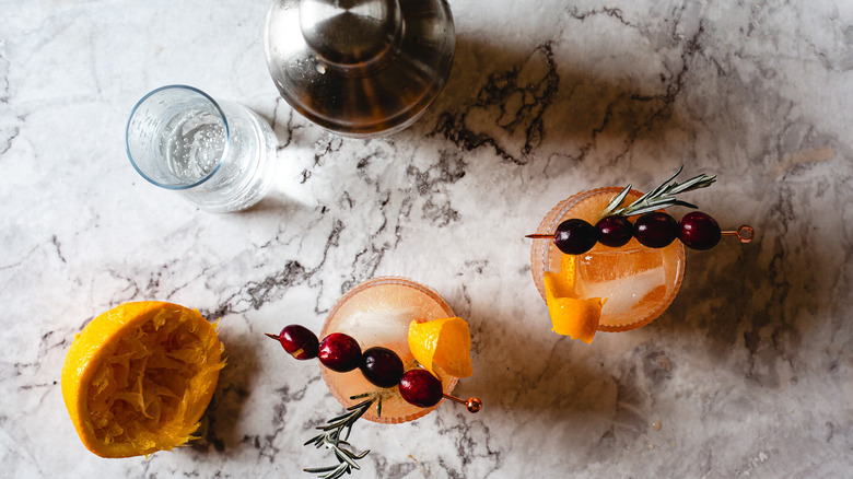 overhead view of two cranberry orange crush cocktails with shaker and orange peel