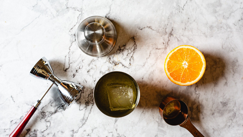 orange half beside shaker with cocktail