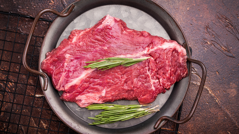 Uncooked skirt steak on a pan with rosemary