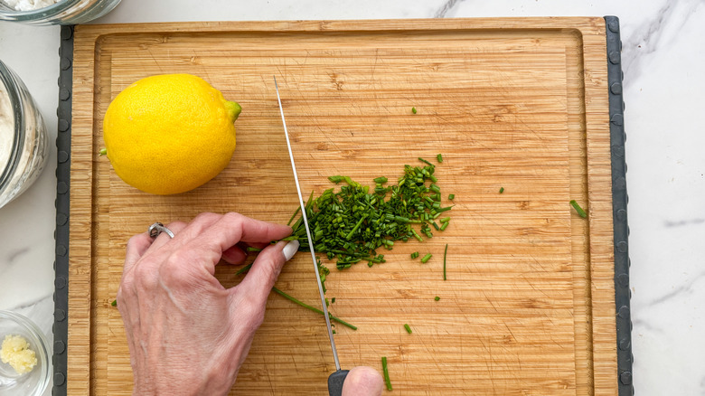 hands chopping chives on board