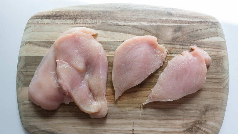 raw chicken cutlets on board