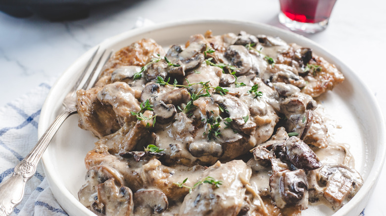 Chicken on plate by crockpot and wine