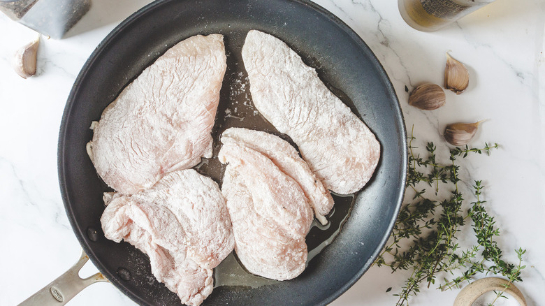 Floured chicken in pan