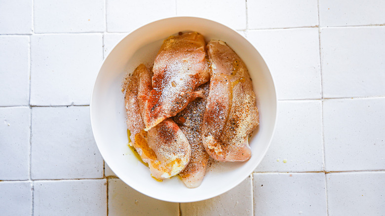 raw chicken with seasonings in bowl
