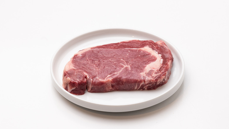 raw ribeye steak on a plate 