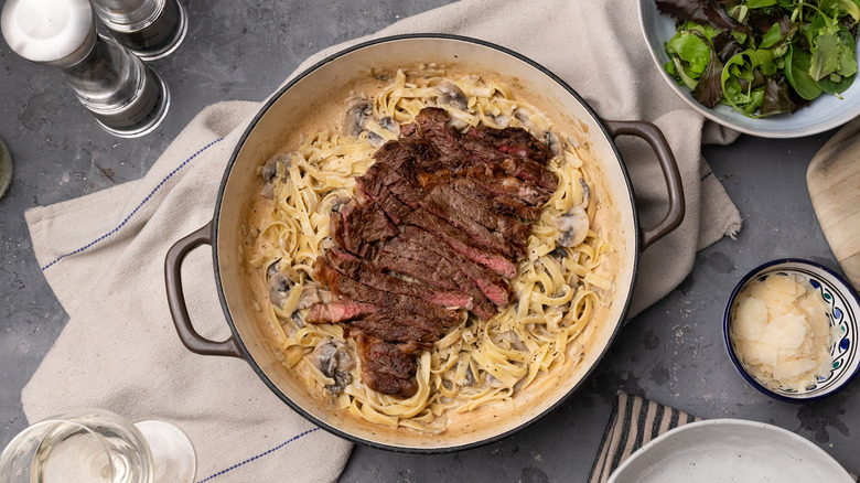 mushroom fettuccine pasta with steak in pan