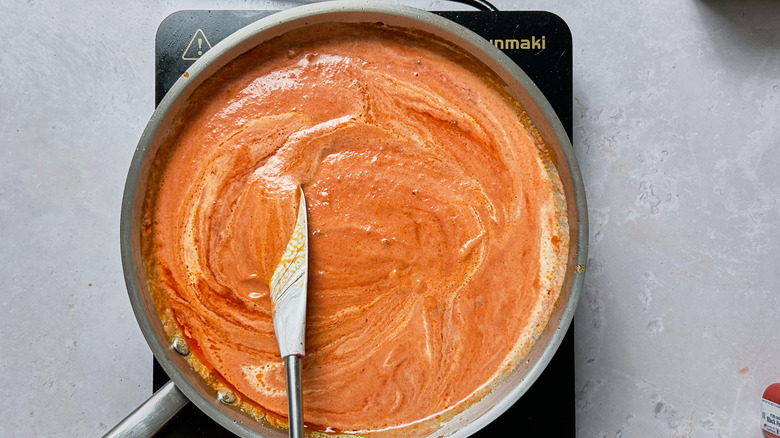 stirring pasta sauce in skillet