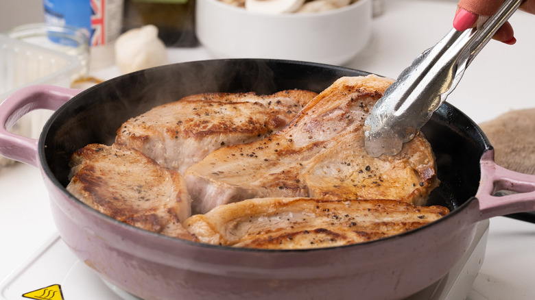 pork chops cooking in pan