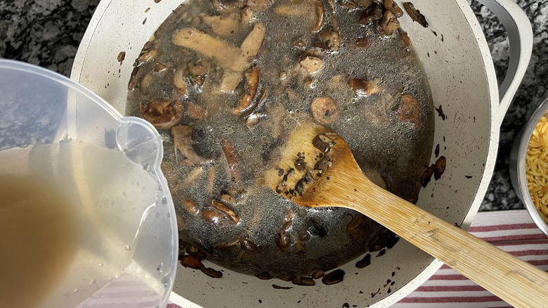 pouring stock onto mushrooms