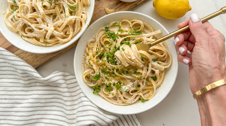 A hand swirling pasta in fork