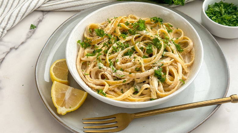 A bowl of garnished pasta on a white plate