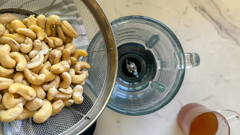 Pouring cashews into a blender