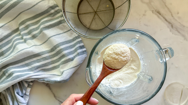 Hand holding wooden spoon full of cashew sauce