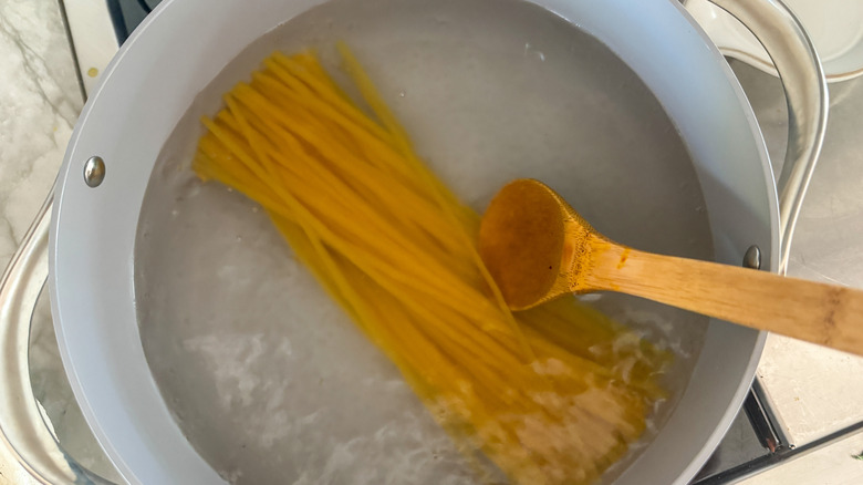 Fettuccine noodles and wooden spoon in pot of boiling water