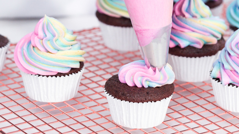 piping multi-colored frosting on cupcakes