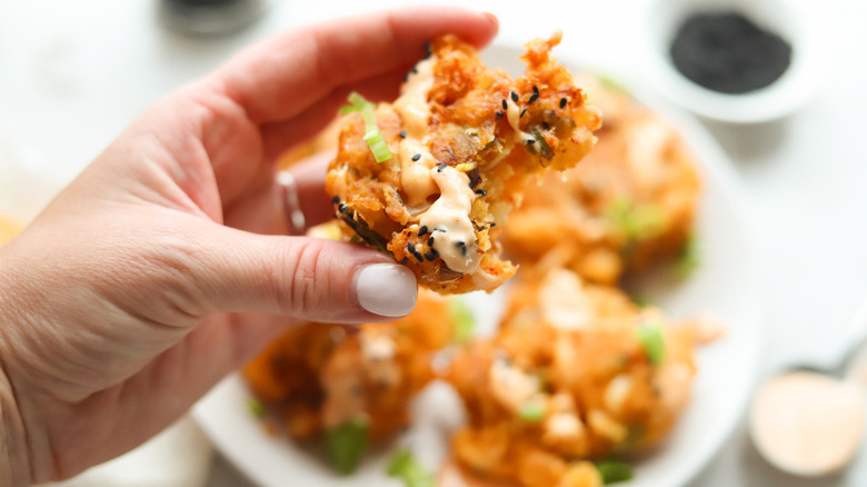 hand holding fritter with sauce