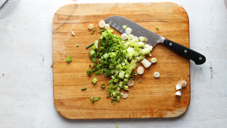 chopped green onions on board