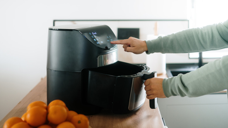 person setting an air fryer to cook