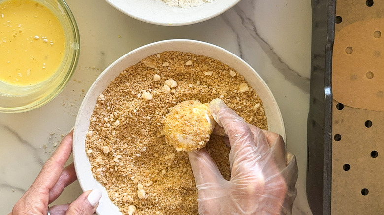 hand dipping mushroom into breading