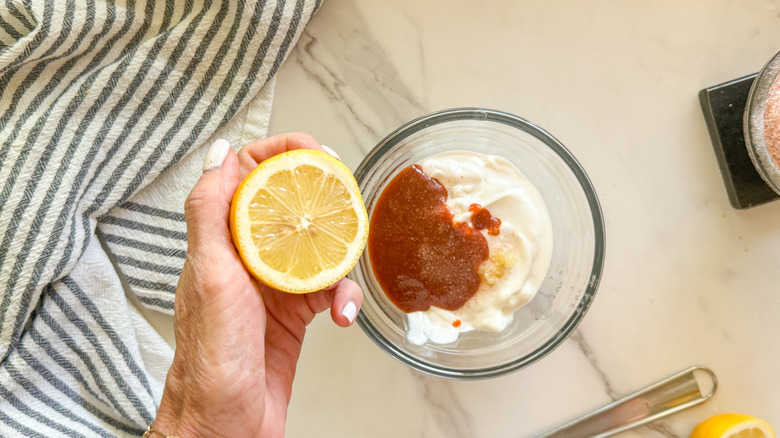 hand adding lemon to sauce