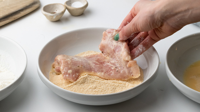 hand holding chicken in breadcrumbs