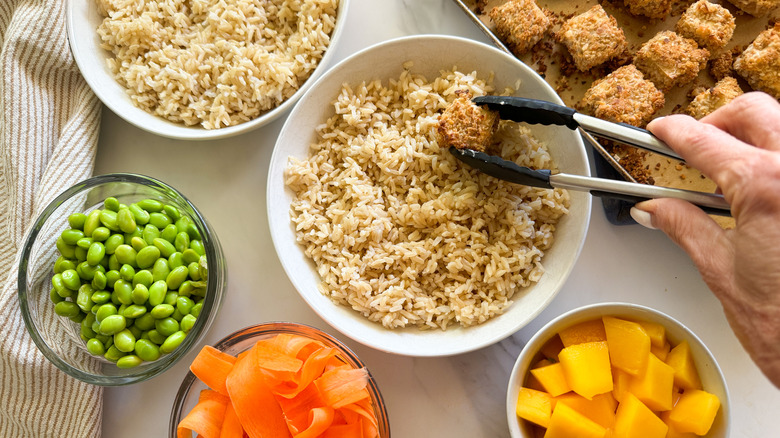 tongs adding tofu to rice