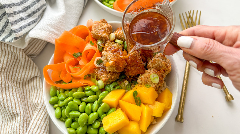 hand pouring sauce on bowl