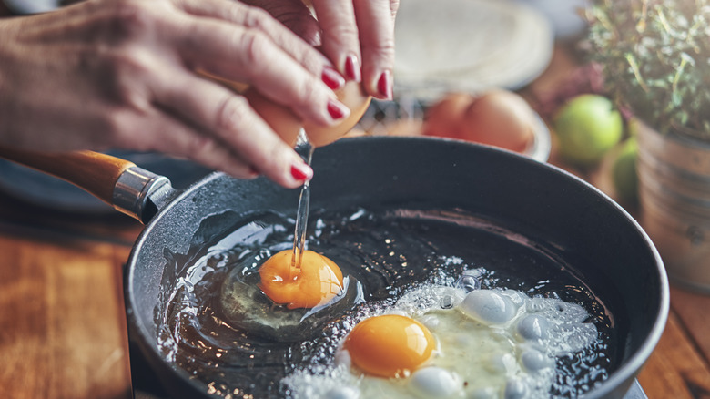 cracking eggs over a frying pan