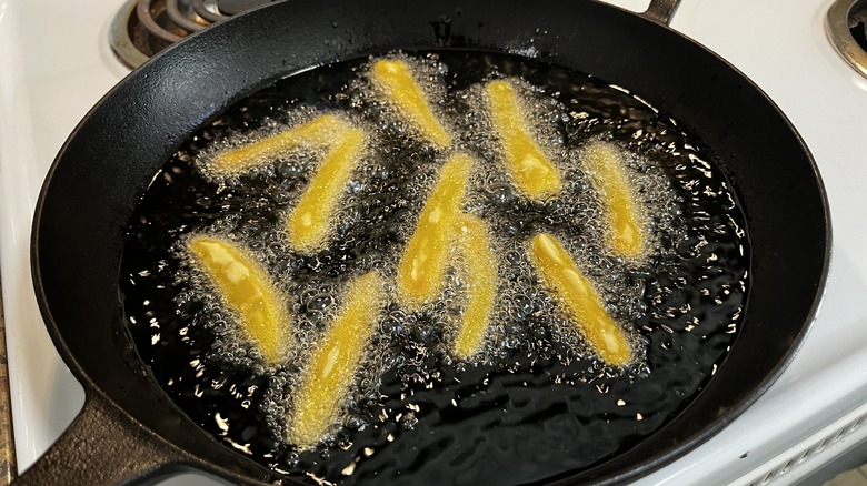 sliced rutabaga frying in skillet of oil