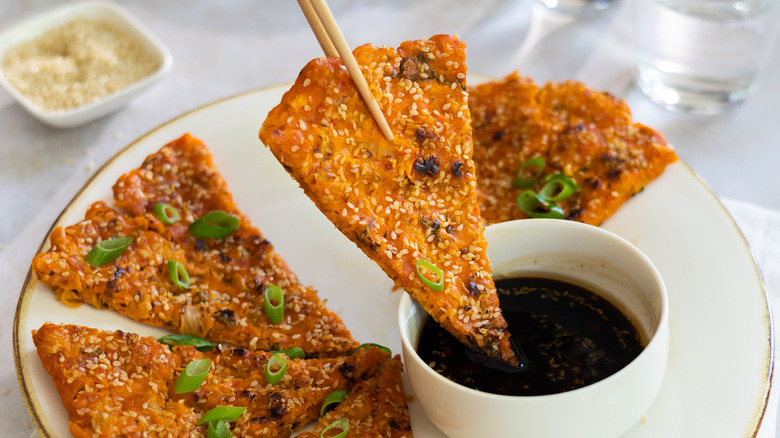 dipping kimchi pancake in sauce