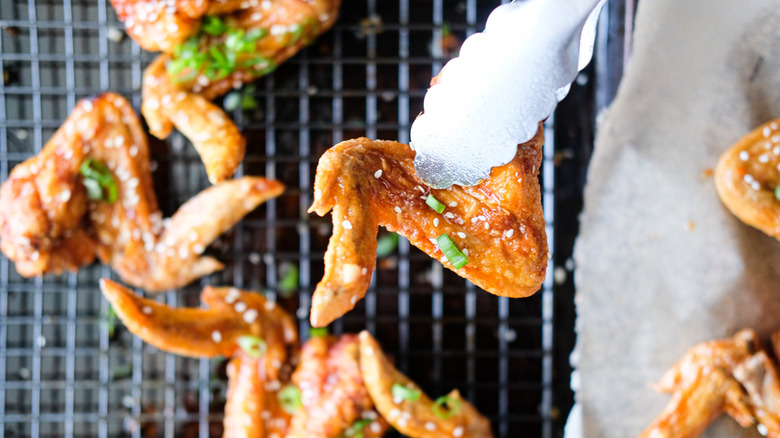 holding chicken wing with tongs