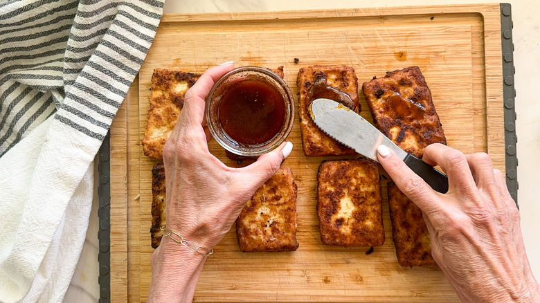 hand spreading tofu with paste