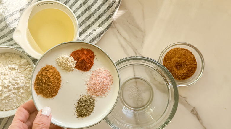 hand adding spices to bowl