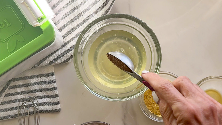 hand adding spice to bowl