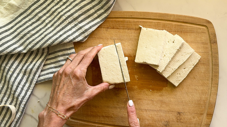 hands slicing tofu