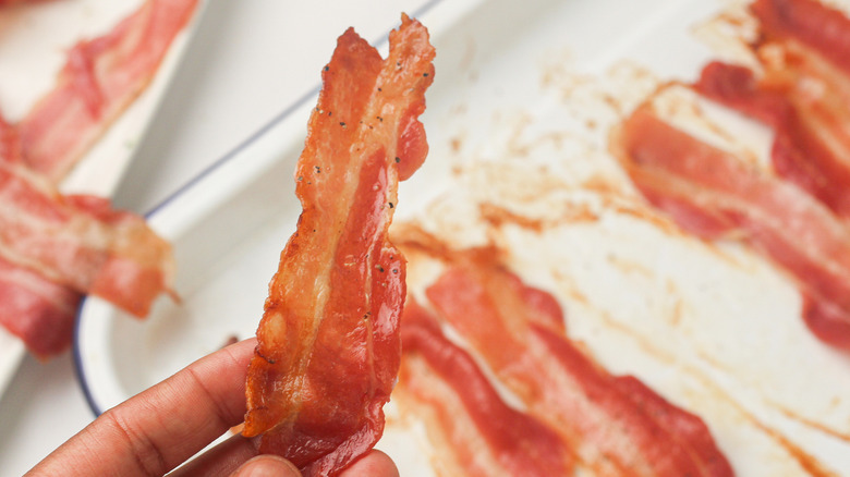 hand holding crispy bacon strip