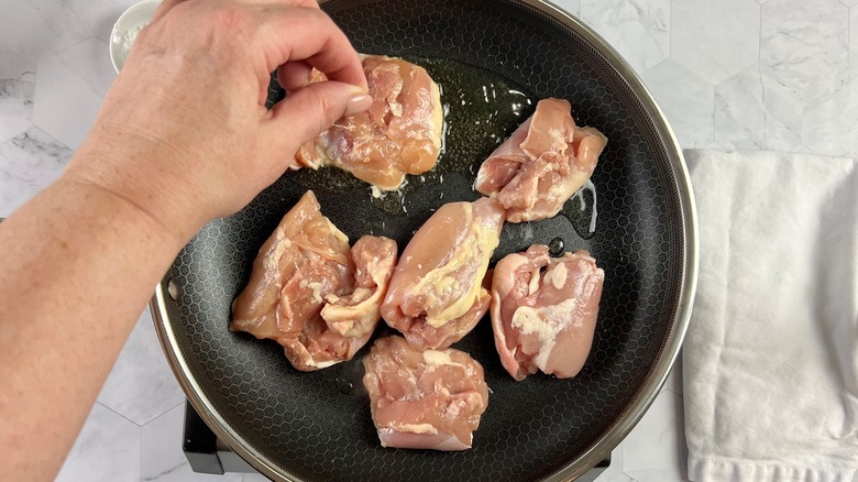 hand sprinkling salt on chicken