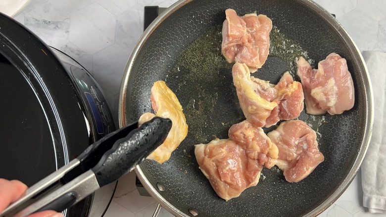 hand holding chicken with tongs