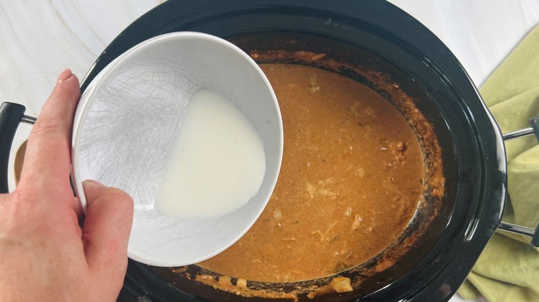 hand pouring cornstarch into pot