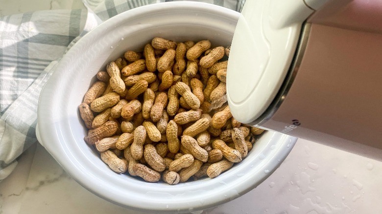 adding hot water to crockpot with peanuts