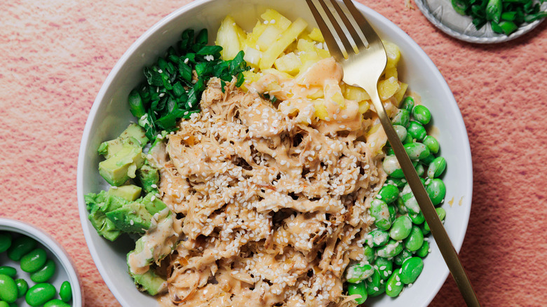 Hawaiian chicken bowl with edamame, scallions in background and a fork