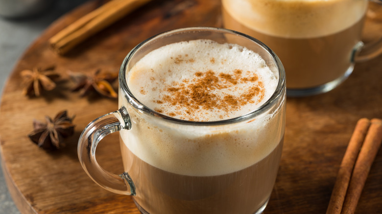 Two glasses of Chai tea with spices on wooden surface