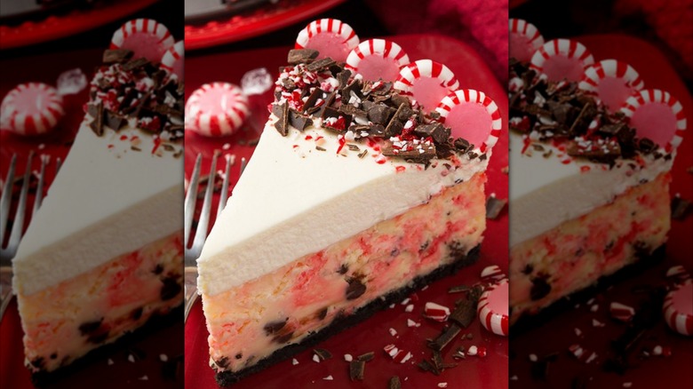 Slice of peppermint cheesecake with fork, peppermints, and chocolate beside it