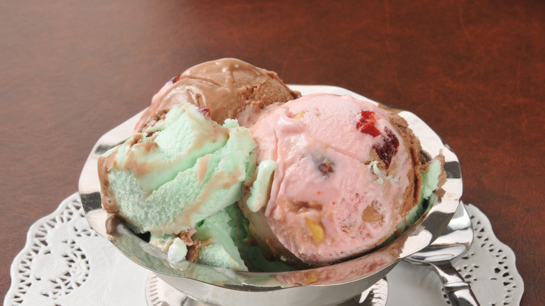 Three scoops of Italian Spumoni ice cream in stainless steel bowl on wooden surface