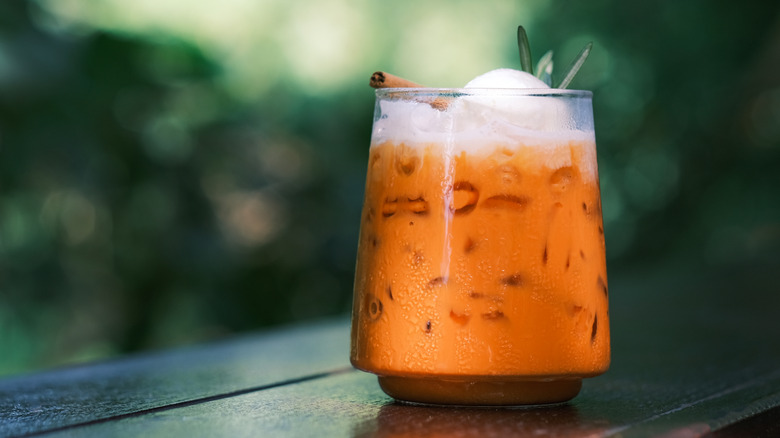 Thai tea with ice cream in glass cup on wooden surface