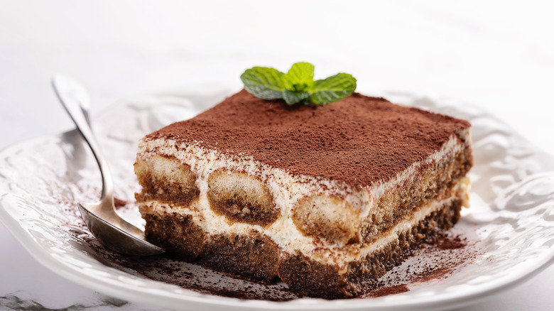 Slice of tiramisu on plate with spoon on side