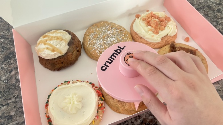 Using cookie cutter to cut into Crumbl chocolate chip cookie